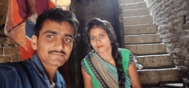 a man and a woman pose for a picture in front of some stairs