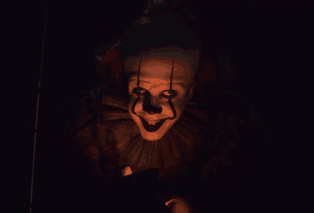 a creepy clown with blood on his face is looking at the camera