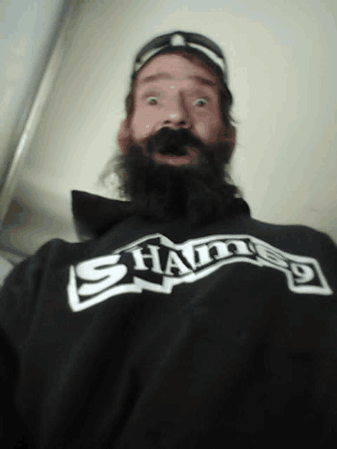 a man with a beard wears a black shirt that says sham