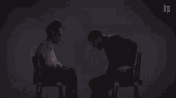 a man and a woman are sitting in chairs talking to each other .