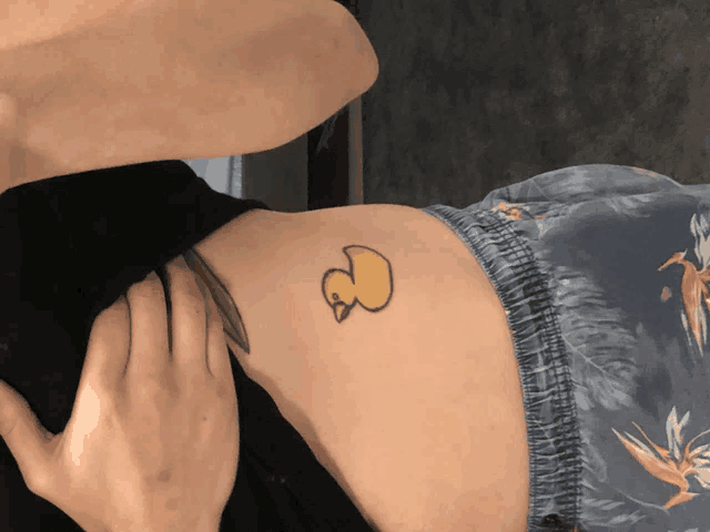 a woman has a tattoo of a yellow duck on her back