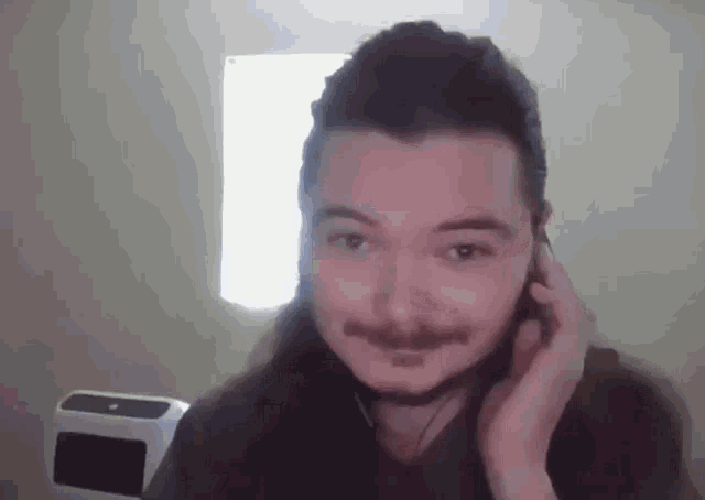 a man with long hair is wearing headphones and smiling .