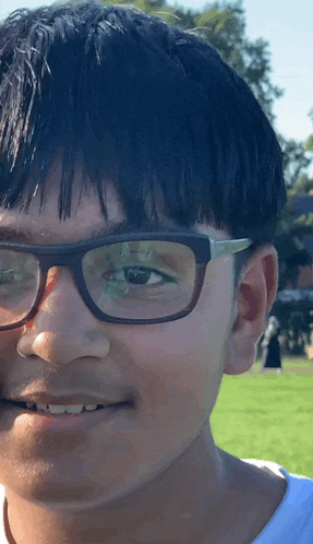 a young boy wearing glasses and a white shirt smiles for the camera