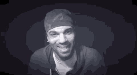 a black and white photo of a man wearing a bandana and a hat with the words `` blocked '' written on his face .