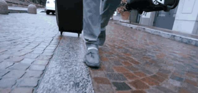 a person walking on a cobblestone street with a suitcase