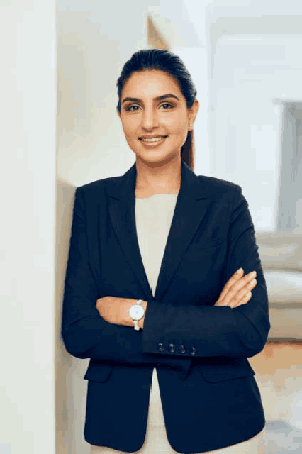 a woman in a suit is standing with her arms crossed and wearing a watch