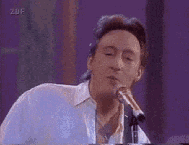 a man is singing into a microphone while playing a piano .
