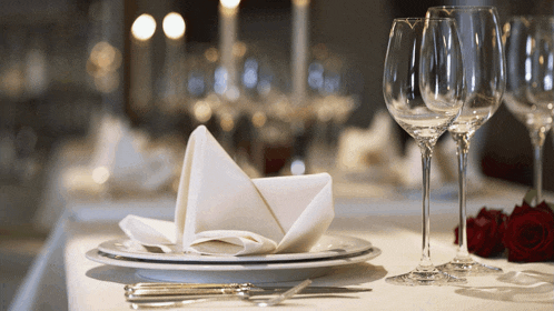 a table set with plates and wine glasses and a napkin folded in half