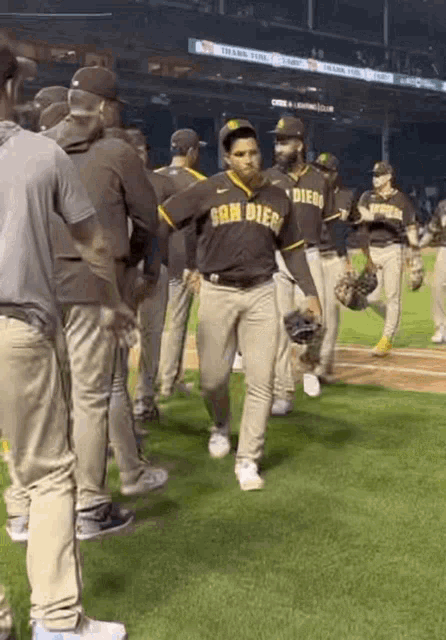 a group of baseball players are standing on a field . one of the players is wearing a san diego jersey .