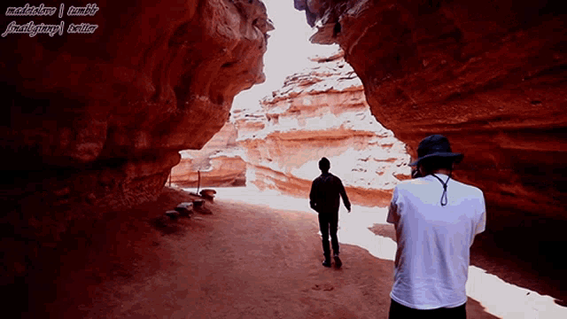 a man taking a picture of another man walking through a canyon with a watermark that says ' madebylove '