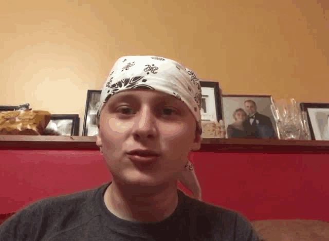 a man wearing a bandana with a picture of a man and woman behind him