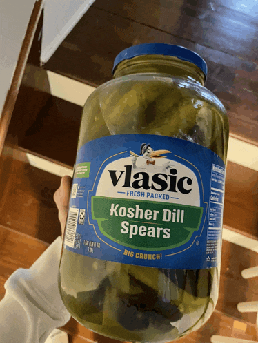 a jar of vlasic kosher dill spears is being held by a person