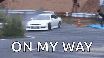 a white car is drifting down a road with the words `` on my way '' written on the bottom .