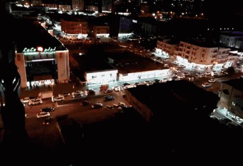 an aerial view of a city at night with a building that says ' arabic ' on the top of it