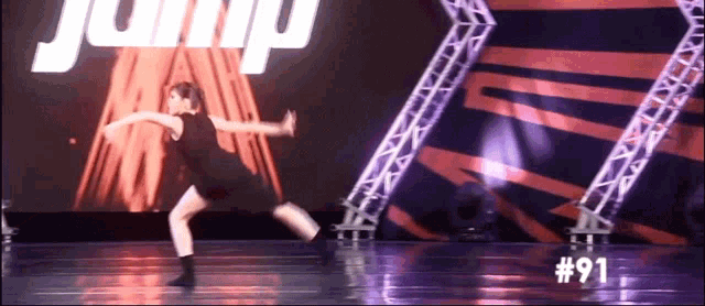 a girl is dancing on a stage with the number 91 in the corner