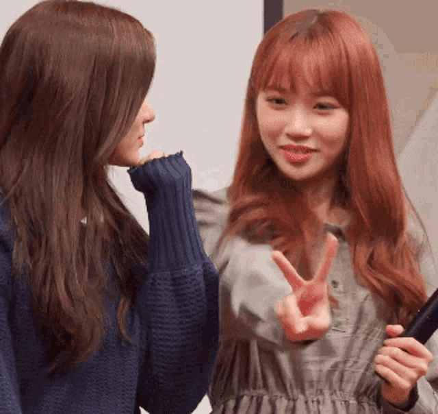 two women are standing next to each other and one of them is giving the peace sign