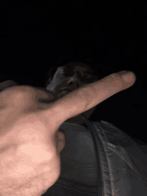 a man is giving the middle finger to the camera in the dark