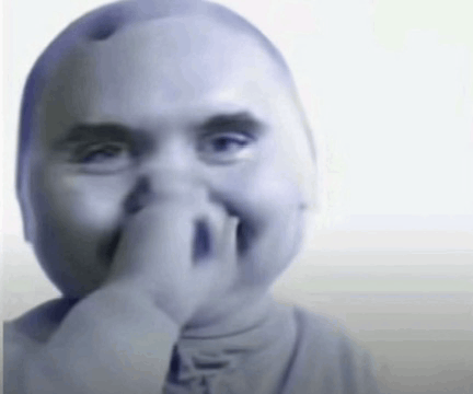 a baby covering his nose with his hand and smiling