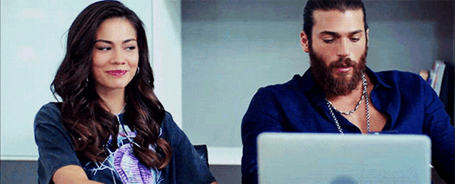 a man and woman are looking at a laptop together