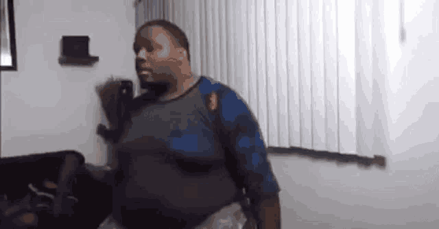 a very fat man is dancing in a living room in front of a window .