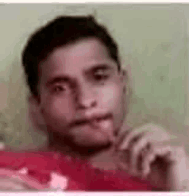 a young man is eating a piece of watermelon and looking at the camera .