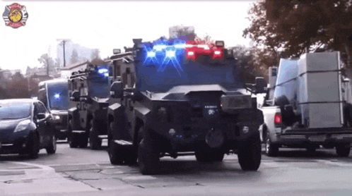 a row of police cars are driving down a street with a fire department logo in the background