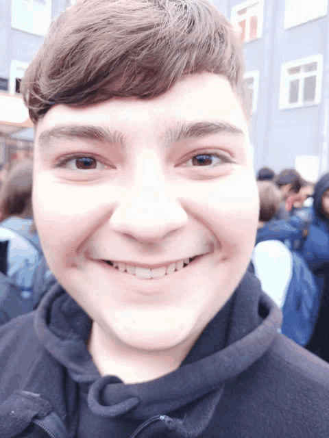 a young man wearing a black jacket with the letter c on it smiles for the camera