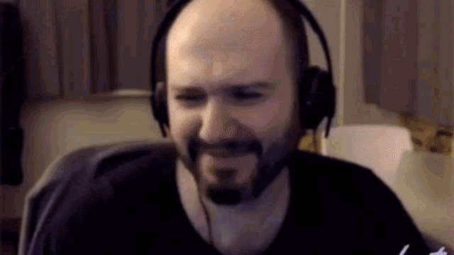 a bald man with a beard wearing headphones is smiling .