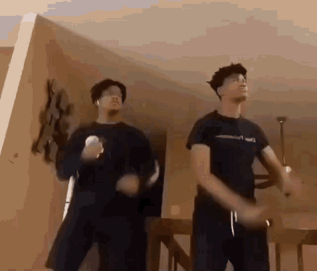 two men are standing next to each other in a living room and dancing .
