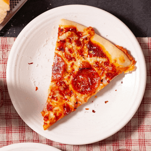 a slice of pepperoni pizza sits on a white plate