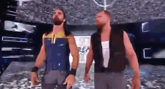 two wrestlers are standing next to each other in a stadium .