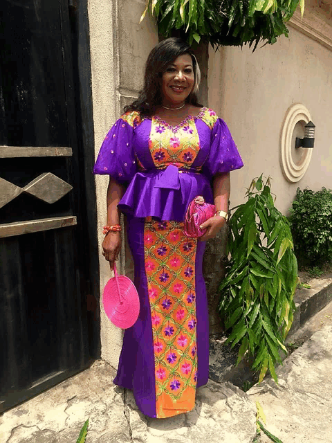 a woman wearing a purple and orange dress holds a pink fan