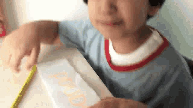 a child is writing the word dad on a piece of paper with a yellow pencil .