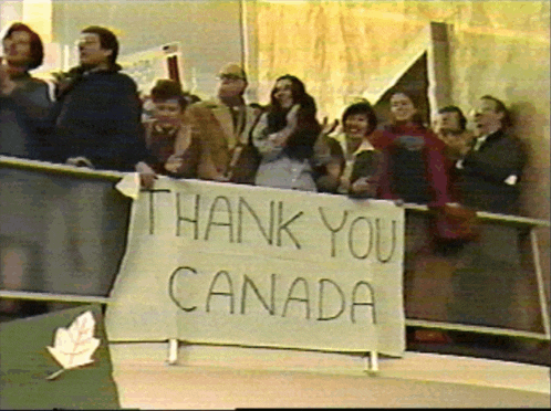 a group of people are standing behind a sign that says thank you canada