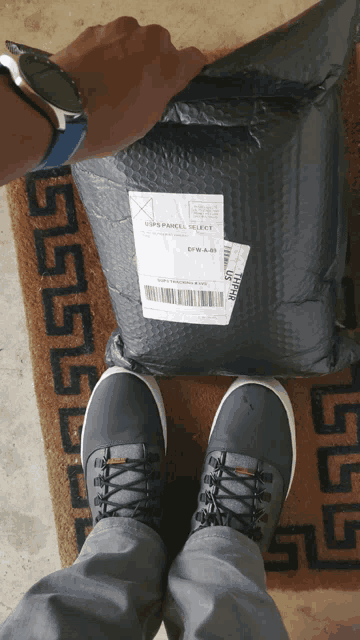 a person standing in front of a package that says usps parcel select