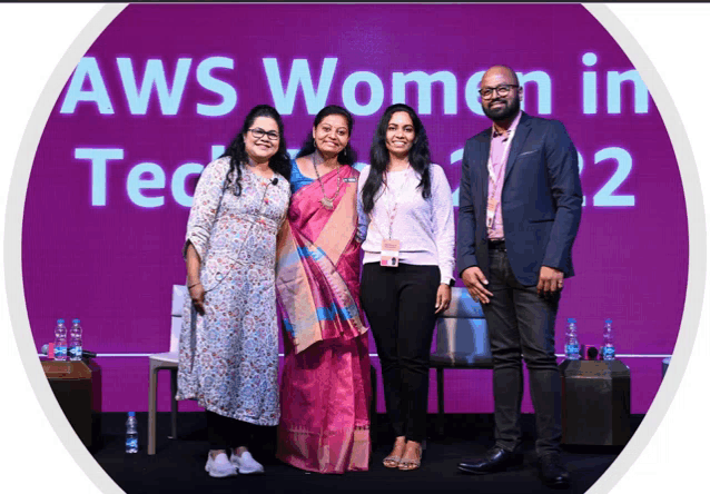 a group of people standing in front of a aws women in tech sign