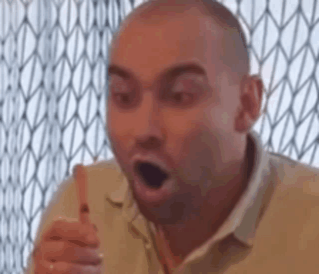 a man is making a surprised face while holding a piece of food in his hand .