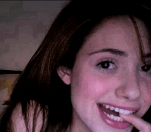 a close up of a woman 's face with her mouth open and her finger in her mouth .