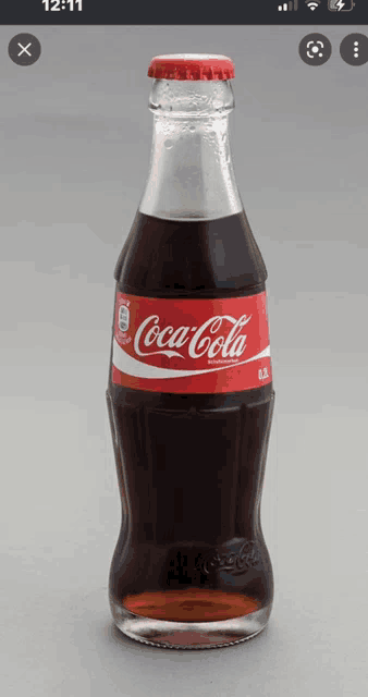 a bottle of coca cola is sitting on a gray surface