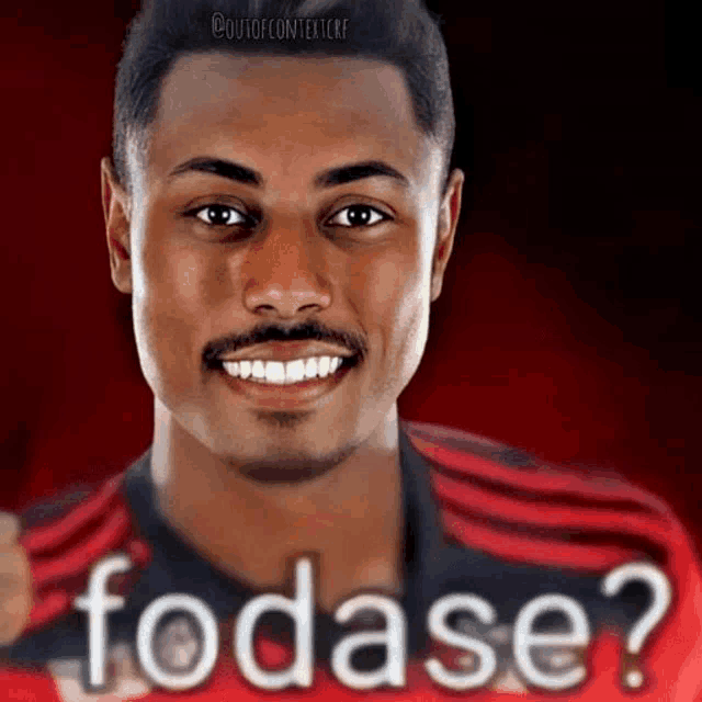 a man with a beard and mustache is smiling and wearing a red shirt with the word fodase on it .