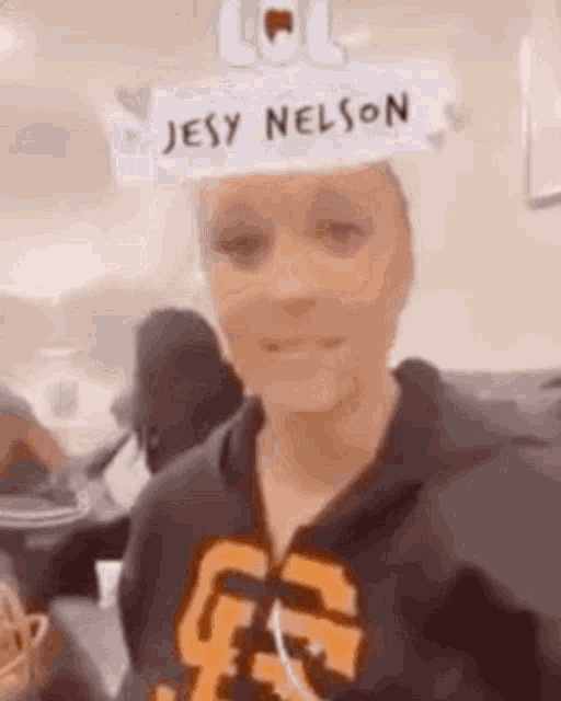 a woman is wearing a paper hat that says jesy nelson .