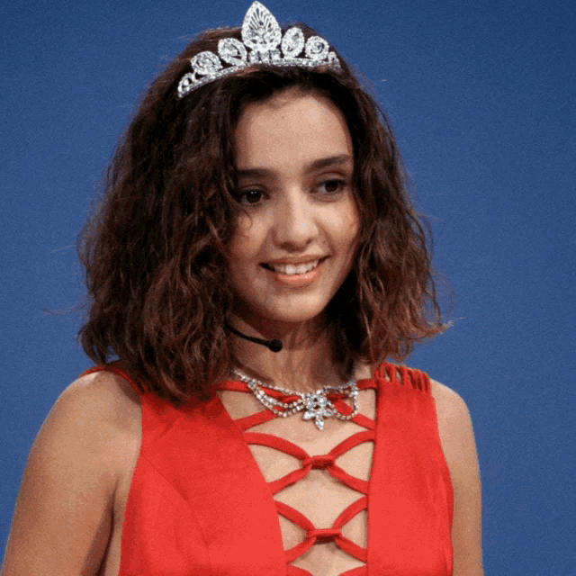 a woman wearing a red dress and a tiara smiles