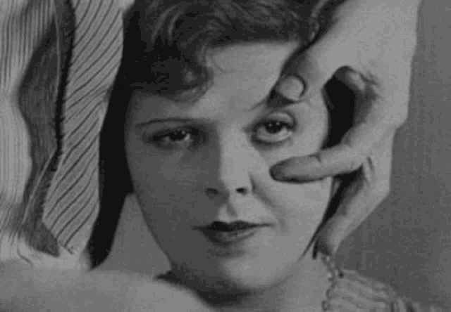 a black and white photo of a woman 's face with a man 's hand on it .