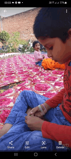 a phone screen shows a child sitting on a blanket