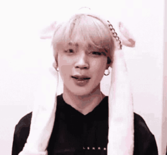 jimin of bts is wearing a pink bunny ear headband .