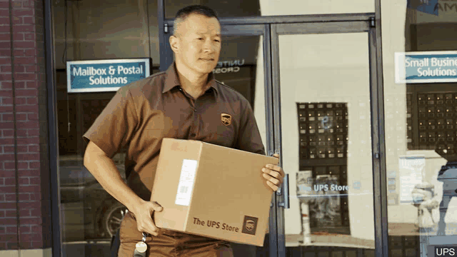 a man in a brown ups uniform carries a cardboard box