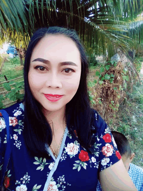 a woman wearing a blue floral shirt smiles for a picture