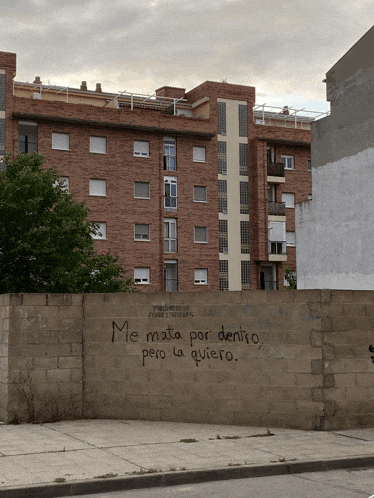 a brick wall with the words me mata por dento pero la quiero written on it