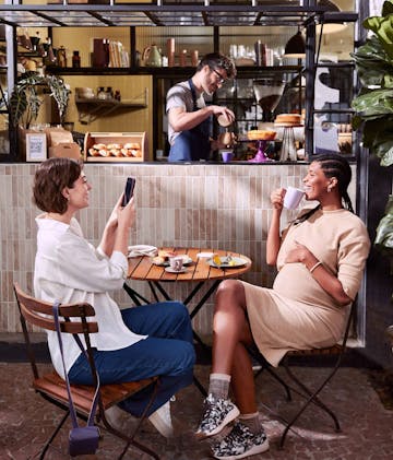 duas amigas sentadas à mesa em uma cafeteria