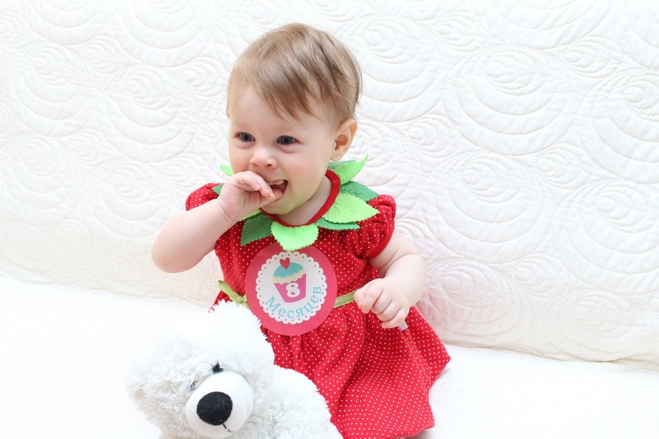 happy baby in a bright suit with a soft toy